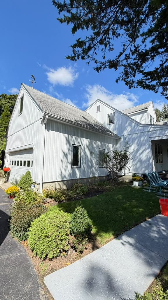 White farmhouse garage wing with vertical board-and-batten siding under a gray shingle roof