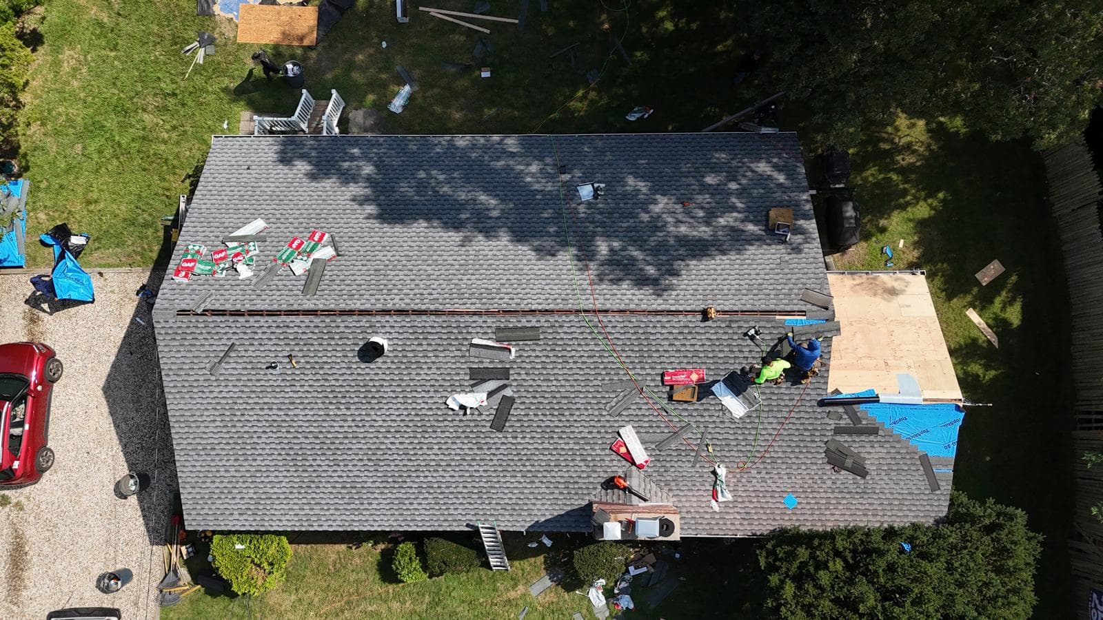 Aerial view of an asphalt shingle roof being installed, with materials laid out on the roof
